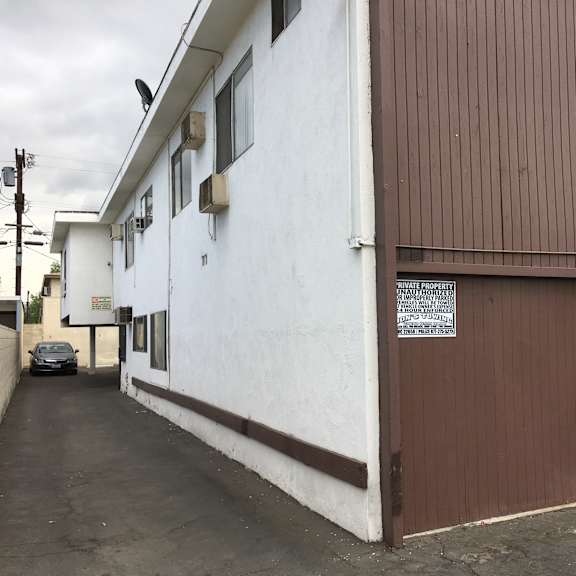 a white building with a brown door and a sign on it.