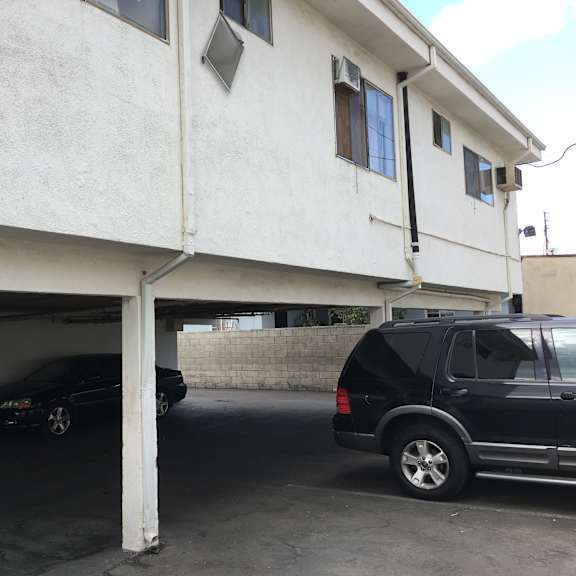 a black car is parked in a garage under a white building.