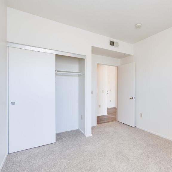a bedroom with white walls and carpet at helix at university village, pomona california