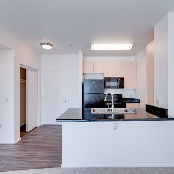 a kitchen with a black counter top and a sink at helix at university village, pomona