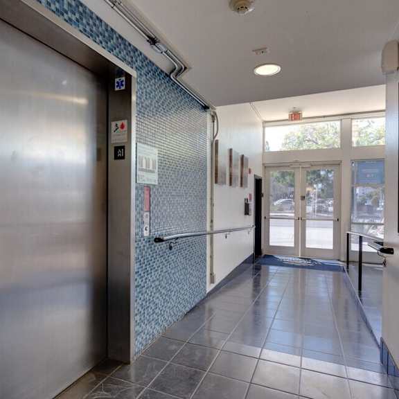 a metal door at the end of a hallway with a blue tile wall at helix at university village, pomona california