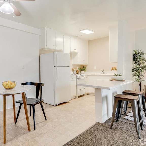 a dining area with a table and chairs and a kitchen with a refrigerator at university park, california