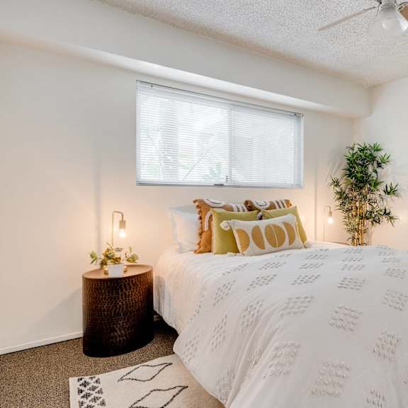 a bedroom with a bed and a plant and a ceiling fan at university park, azusa
