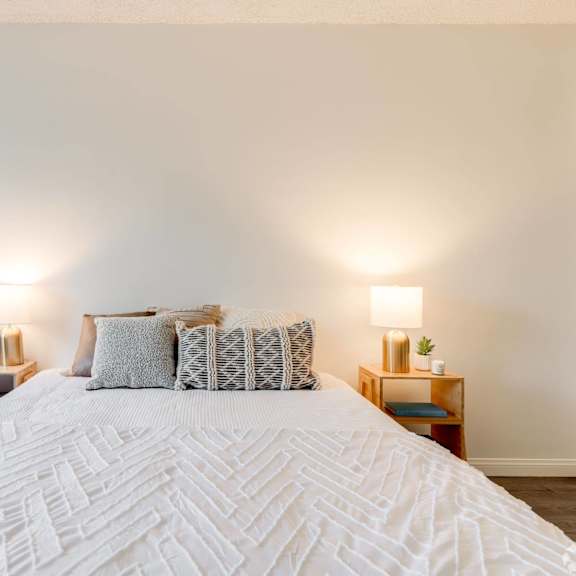 a bedroom with a large white bed and white walls at university park, azusa