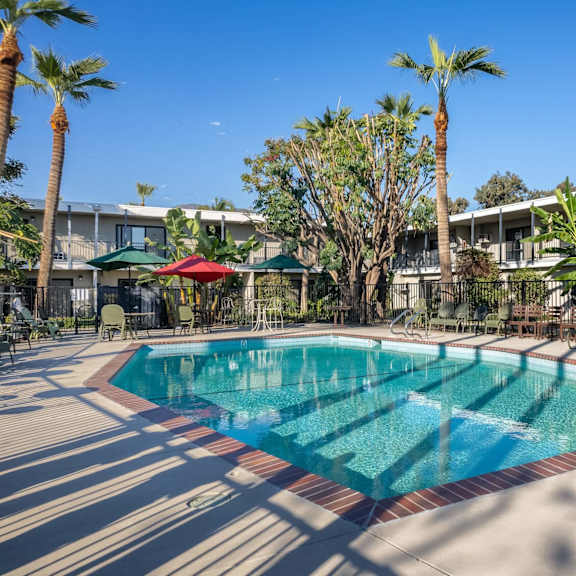 a swimming pool with palm trees and a building in the background at university park, azusa, ca 91702