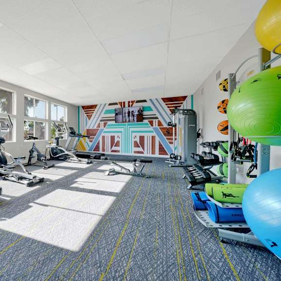 a gym with treadmills and weights in a room with windows at sunnymead apts apartments, moreno valley