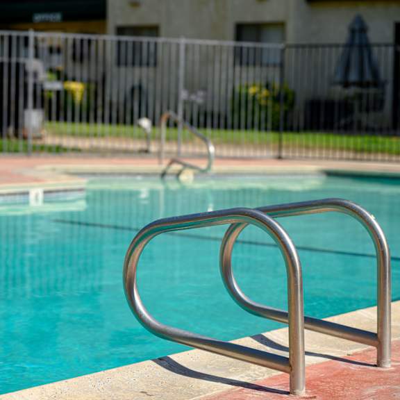 a swimming pool with a ladder in front of a building at park columbia apts, hemet, 92544