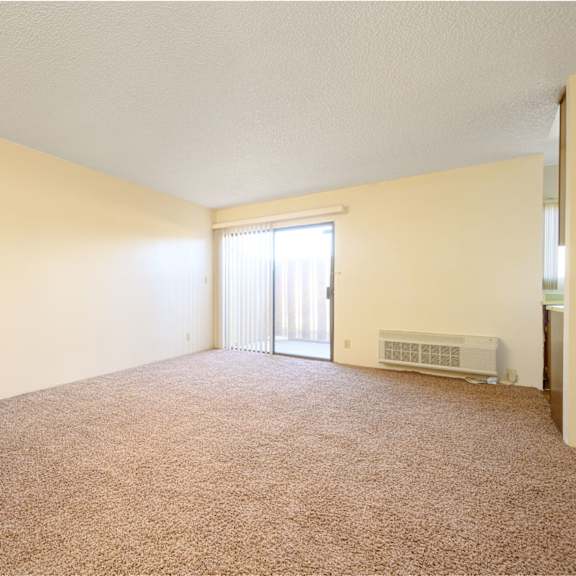 an empty living room with a door leading to a balcony at park columbia apts, hemet california