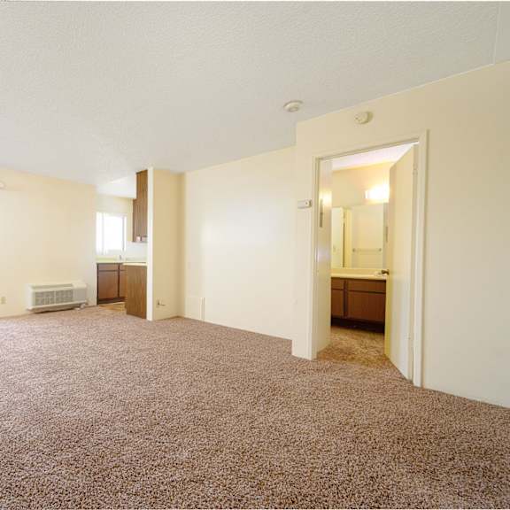 a bedroom with a large window and a door leading to a kitchen at park columbia apts, hemet, 92544