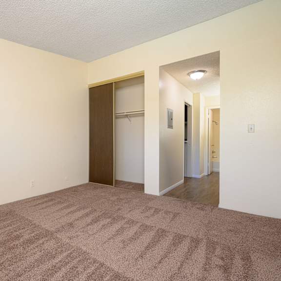 a bedroom with a carpeted floor and white walls at park columbia apts, hemet
