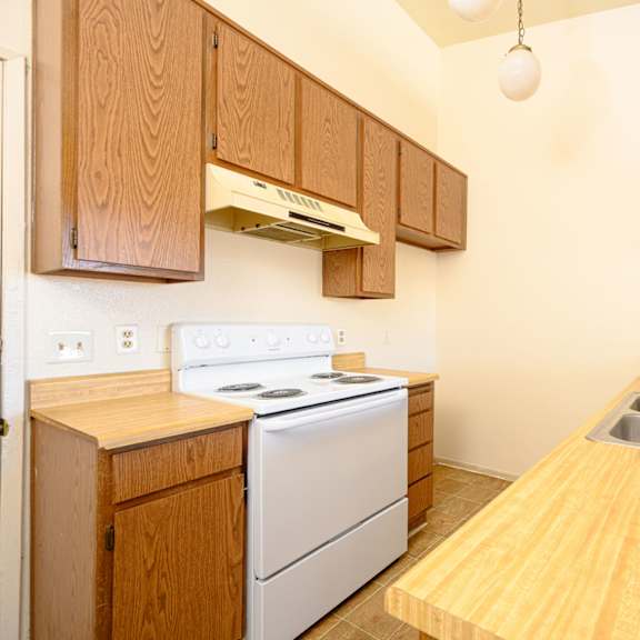 a kitchen with wooden cabinets and white appliances at park columbia apts, hemet, ca