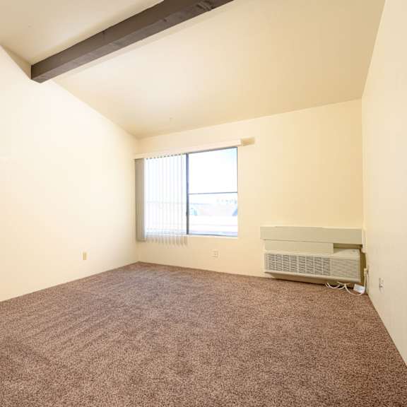 a bedroom with carpeted floors and a large window at park columbia apts, california, 92544