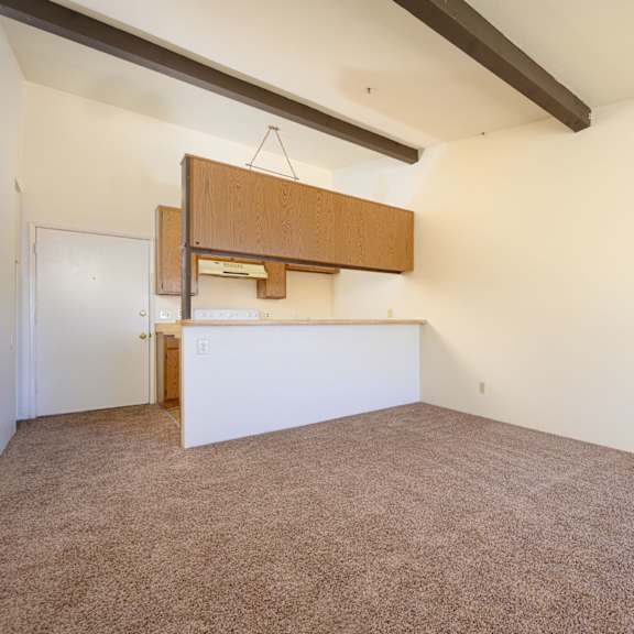 a kitchen and dining area in a room with white walls and carpet at park columbia apts, hemet, ca 92544