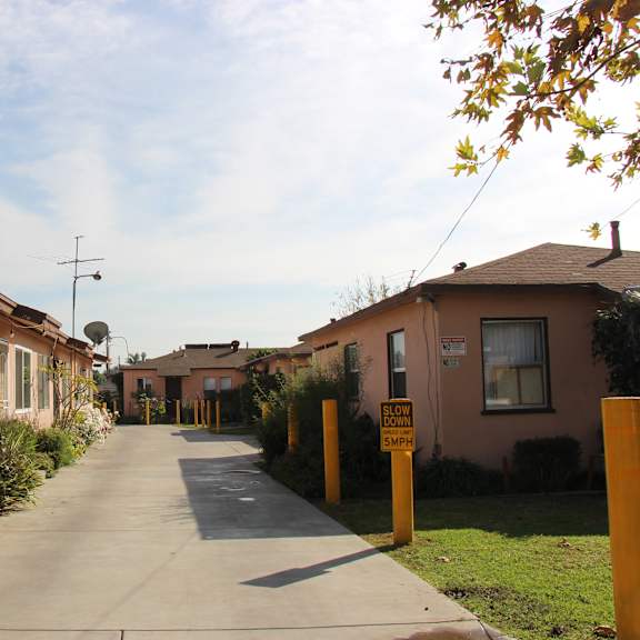 a residential street with houses on both sides and a sign on the right side of the street.