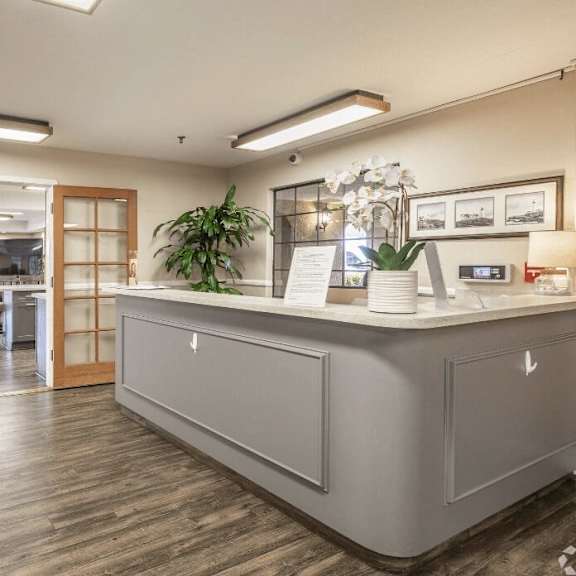 a reception area with a blue couch and a counter in a lobby at huntington terrace north senior, huntington beach, ca