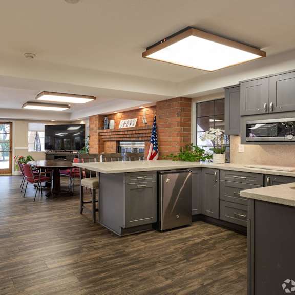 a clubhouse with a kitchen and a living room with a table and chairs at huntington terrace north senior, california, 92648