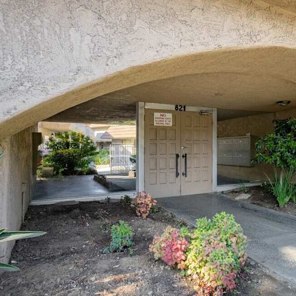 the front door of a building with a flower garden in front of it at north view terrace, montebello, ca 90640