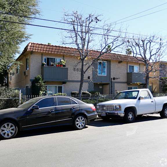 a black car is parked on the street in front of a house.