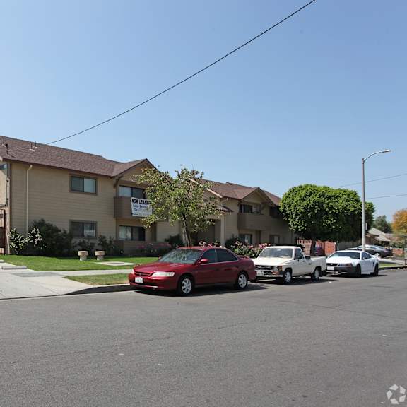 a red car is parked in front of a house with a fence.