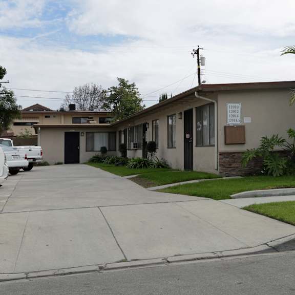 a house with a driveway and a palm tree in front.
