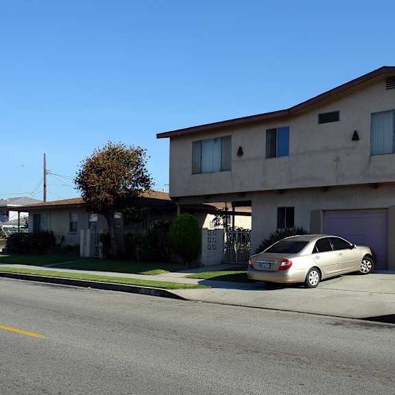 a beige house with a car parked in front.