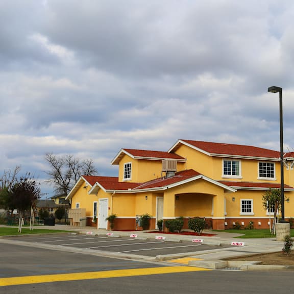a yellow building with a red roof and a parking lot in front.