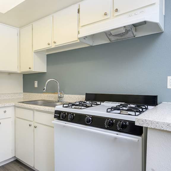 a kitchen with white cabinets and a white stove top oven at sagewood gardens senior apartments, hacienda heights