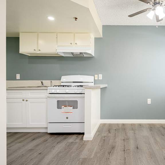a kitchen with a stove and a ceiling fan at sagewood gardens senior apartments, hacienda heights