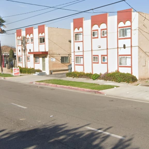 a street view of a red and white building with a green fence in front.