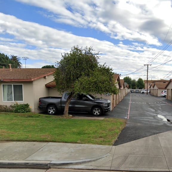 a residential street with houses on both sides and cars parked on the side.