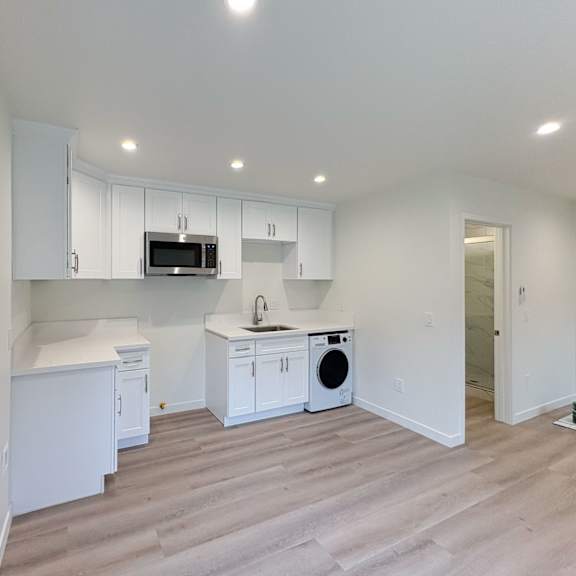 a kitchen with white cabinets and a microwave above the sink.