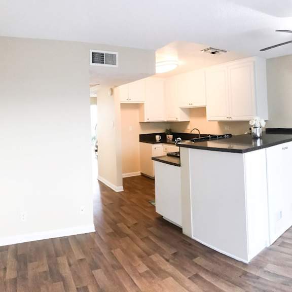 an empty kitchen with white cabinets and a ceiling fan at terramonte apartment homes, pomona, california
