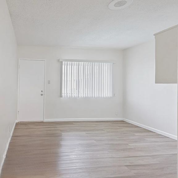 a room with a wooden floor and a window with blinds.
