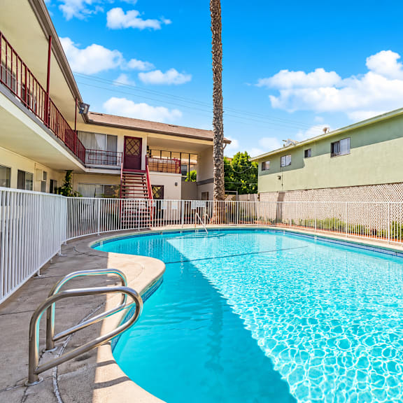 a swimming pool surrounded by a fence and a building in the background.