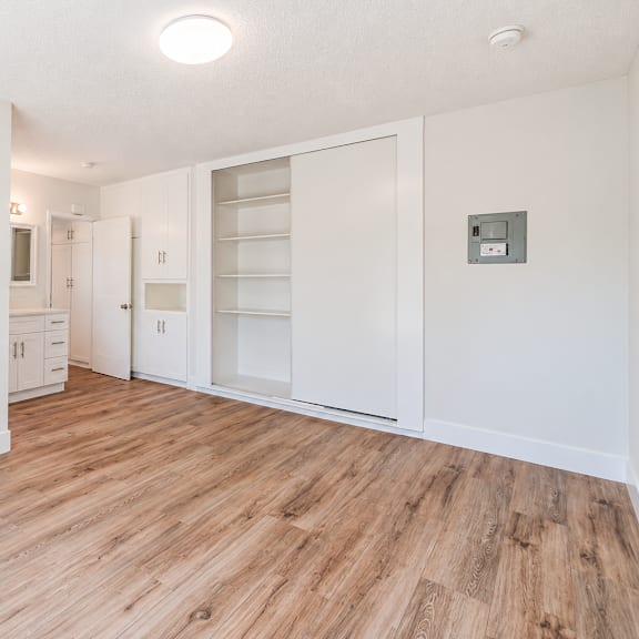 a room with wooden floors and white walls, with a door on the right side.