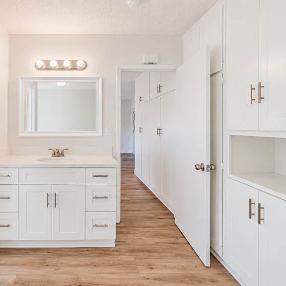 a white bathroom with a toilet, sink, and mirror.