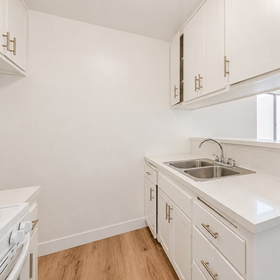 a white kitchen with wooden floors and white cabinets.