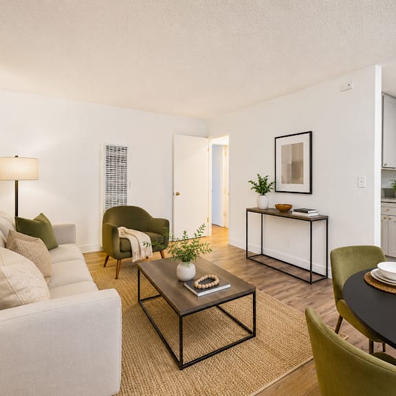a living room with a white couch, a coffee table, and a dining table set for two.