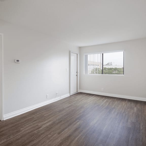 an empty living room with white walls and wood flooring at huntington terrace north senior, huntington beach