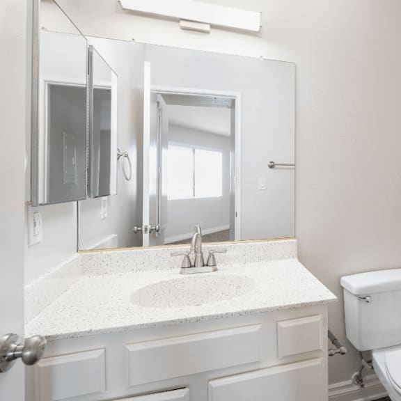a bathroom with a toilet and a sink and a mirror at huntington terrace north senior, huntington beach, ca