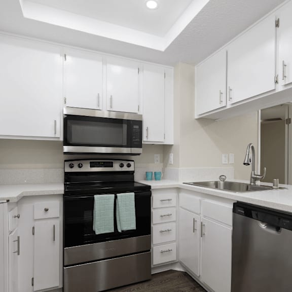 a kitchen with white cabinets and black and white counter tops at huntington terrace north senior, huntington beach california