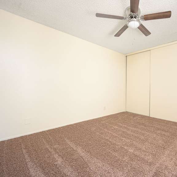 a bedroom with white walls and a ceiling fan at villa hemet, hemet california