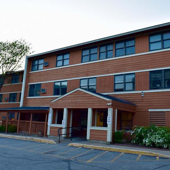 a brown building with a parking lot in front.
