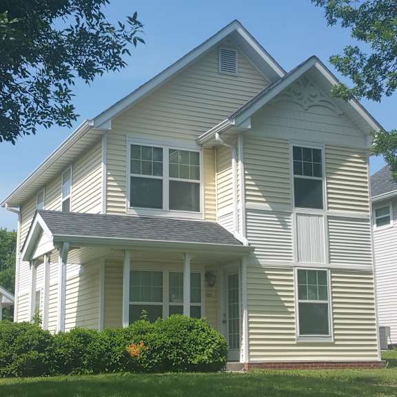 a white house with a grey roof and a small porch.
