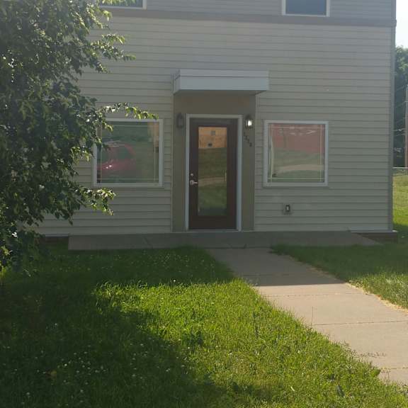 a house with a grey siding and a red car in the driveway.