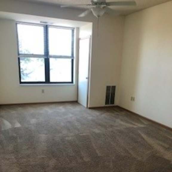 a room with a carpeted floor and a ceiling fan.