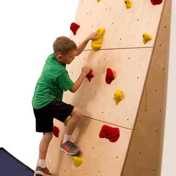 a boy climbing a wall with red and yellow holds.