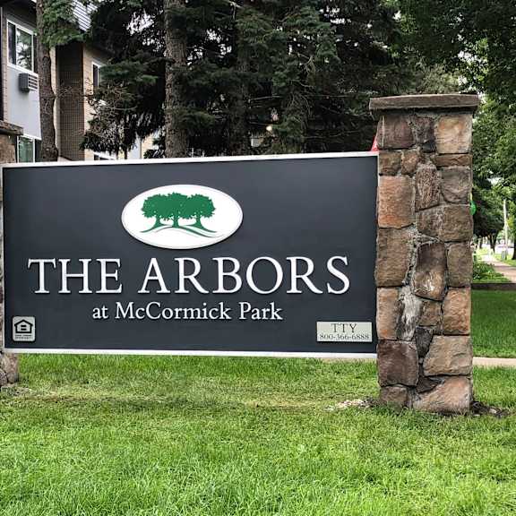 a sign for the arbors at mccormick park stands in front of a building.