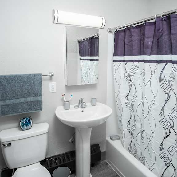 a white toilet with a blue towel hangs on a wall next to a sink and a mirror.