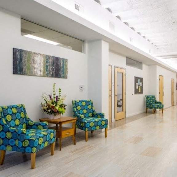 a hallway with chairs and a table with flowers on it.